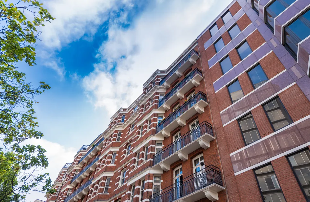 Red brick cooperative or condominium apartment building with balconies viewed from street level.