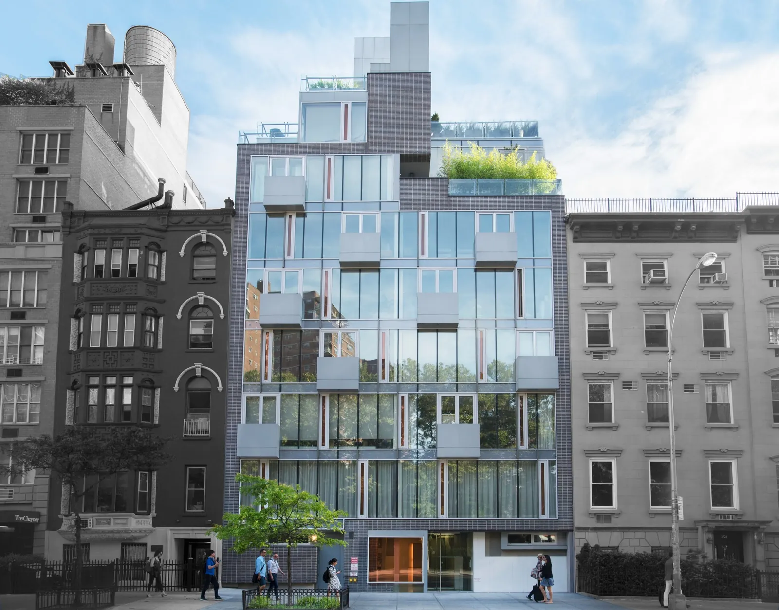 Modern glass-fronted residential building between older neighboring buildings in downtown NYC.