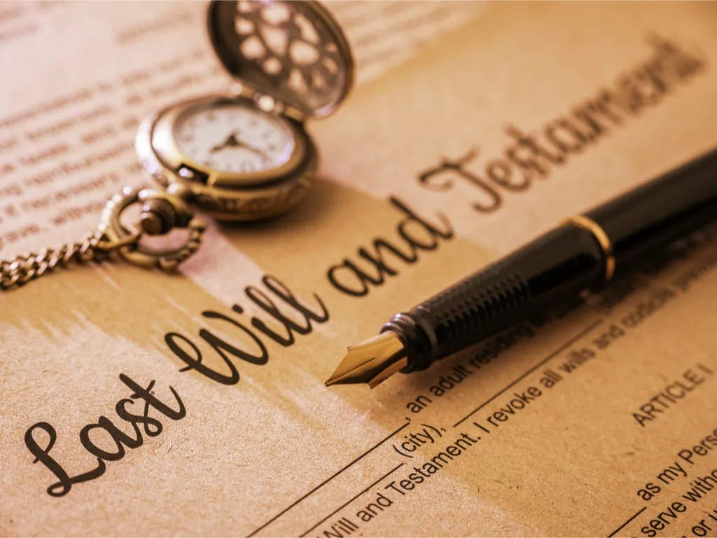 Close-up of a last will and testament document with a fountain pen and pocket watch.